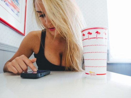 girl with down blouse looking at her phone with blonde hair at a fast food restaurant