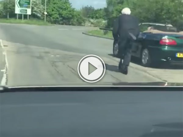 An old Man scooters down a busy road (Video)
