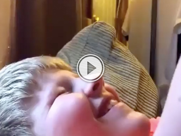 A blonde kid smiling on the bed!