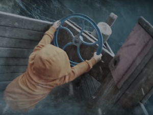 Kid in brown hoodie manning the steering wheel in a boat.