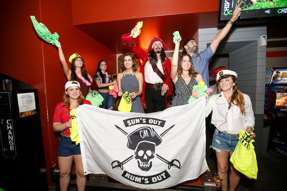 The pirate captain pose with his flag held by other drunk passengers in a party