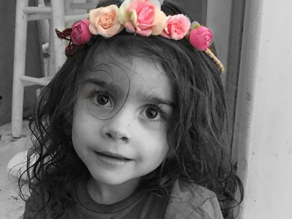 Kid girl with big eyes and flowers on her head looks into the camera!